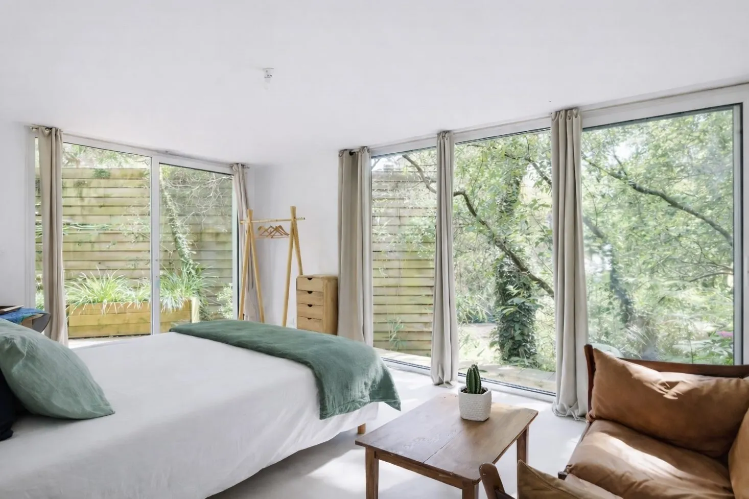 Chambre des Pins : lit face aux baies vitrées d'angle donnant sur les arbres et la terrasse