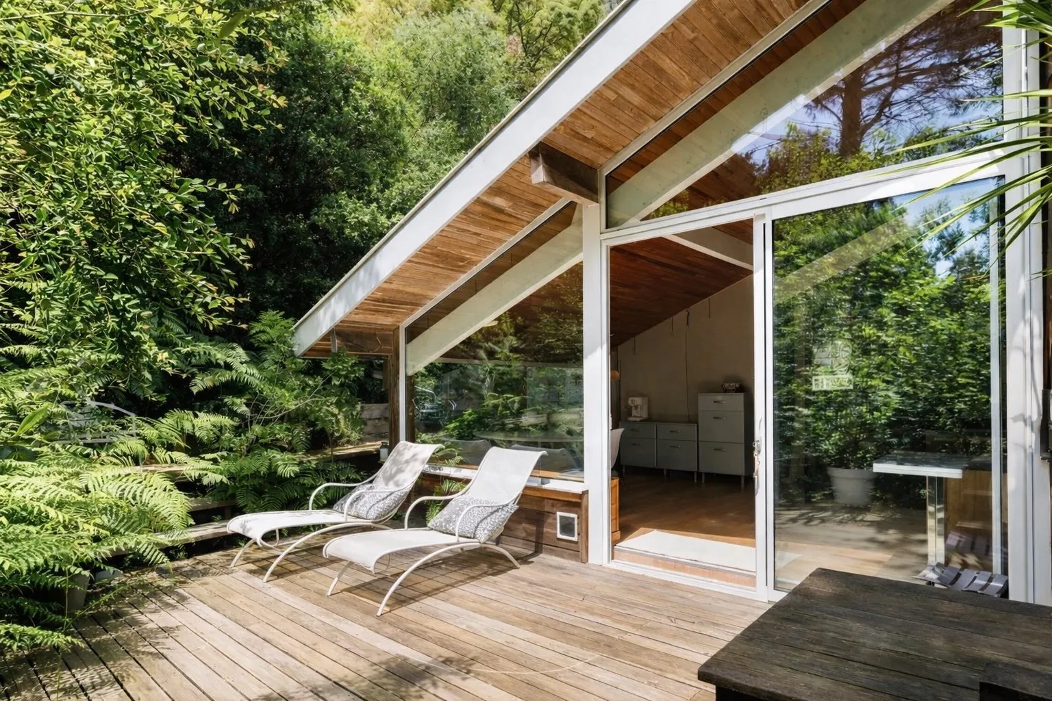 Wooden terrace of Studio Augusta with two sun loungers and a view over the garden and greenery