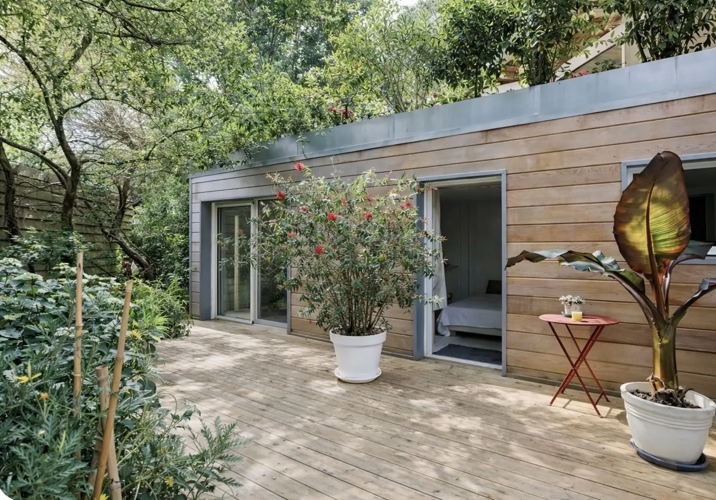 Terrasse en bois de la Chambre Cosy avec plantes en pot et façade bardée de bois