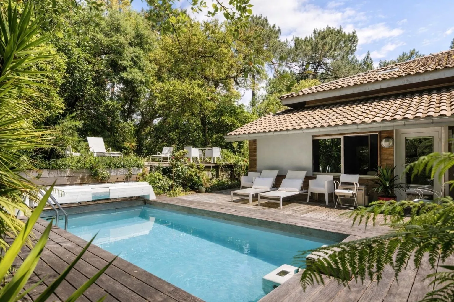 Pool of the property bordered by a wooden terrace and sun loungers